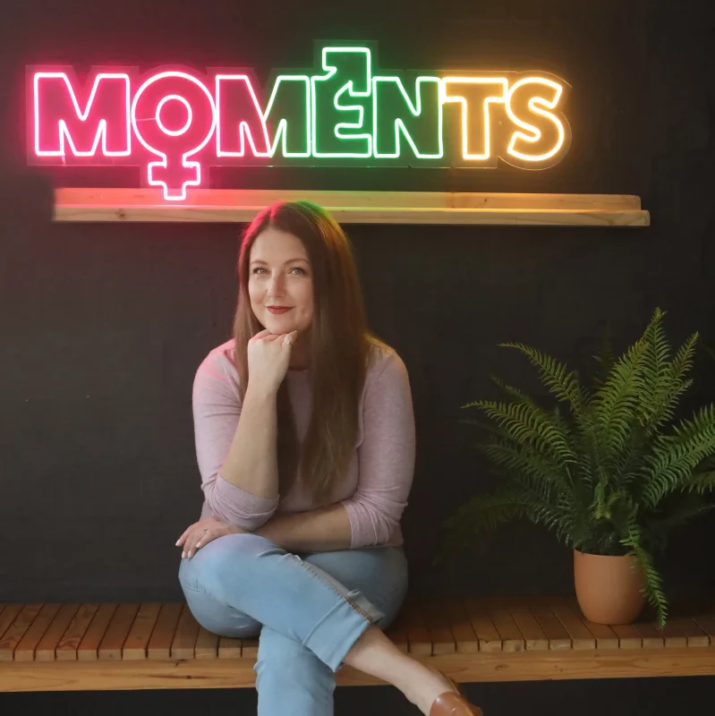 Madge Booth With The MOMents Podcast Sign